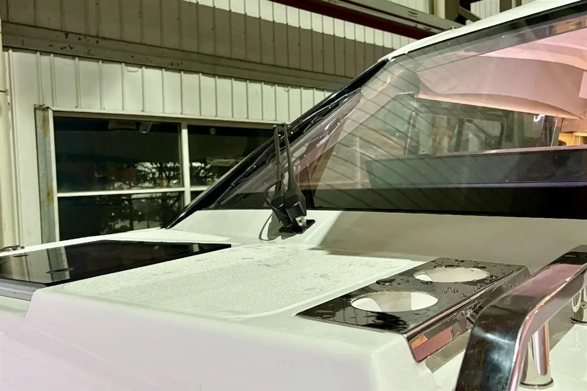 Close-up of a boat's dashboard featuring a windshield wiper and surface with a small black panel and cup holders.